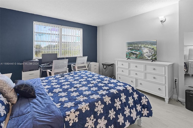 bedroom with a textured ceiling and light hardwood / wood-style flooring