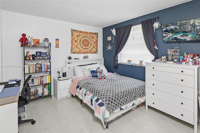 bedroom with light wood-type flooring and a textured ceiling