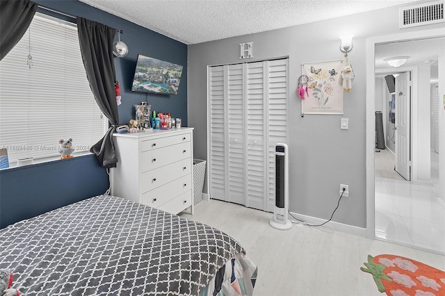 bedroom with a closet, light hardwood / wood-style floors, and a textured ceiling