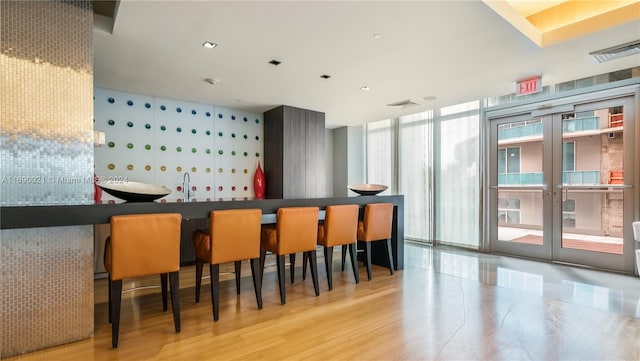 bar with expansive windows, sink, and light hardwood / wood-style flooring