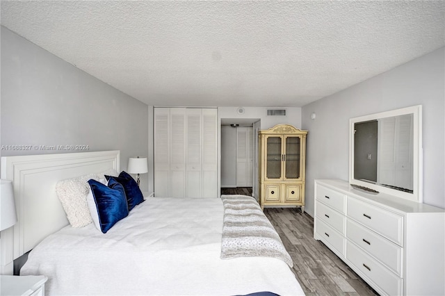 bedroom with a closet, hardwood / wood-style floors, and a textured ceiling