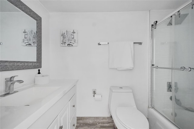 full bathroom featuring hardwood / wood-style flooring, vanity, toilet, and combined bath / shower with glass door