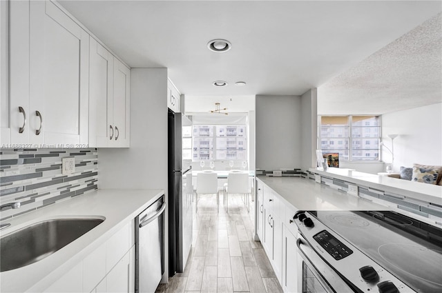 kitchen with light wood-type flooring, tasteful backsplash, stainless steel appliances, sink, and white cabinets