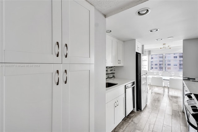 kitchen with white cabinets, sink, stainless steel appliances, and tasteful backsplash