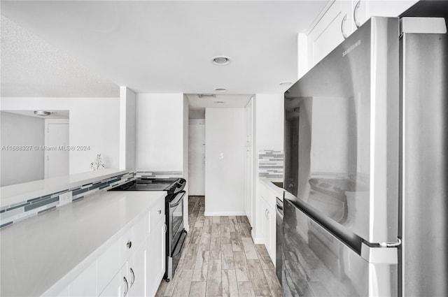 kitchen with white cabinets, stainless steel appliances, and light hardwood / wood-style flooring