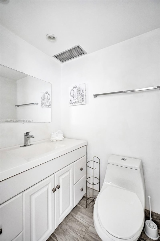 bathroom with hardwood / wood-style flooring, vanity, and toilet