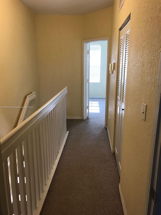 hall featuring dark colored carpet