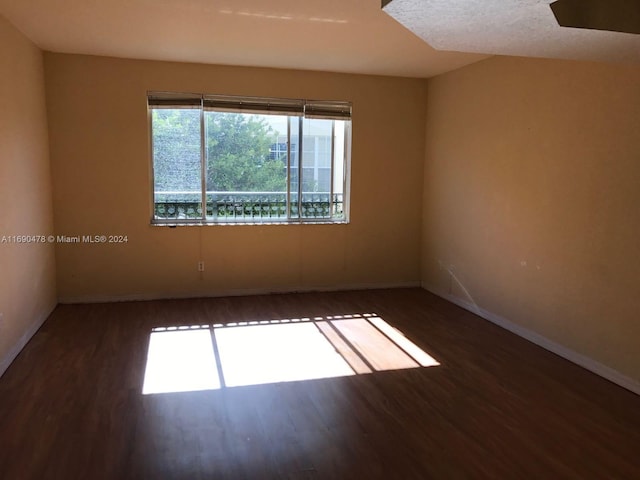 empty room featuring a textured ceiling and dark hardwood / wood-style floors