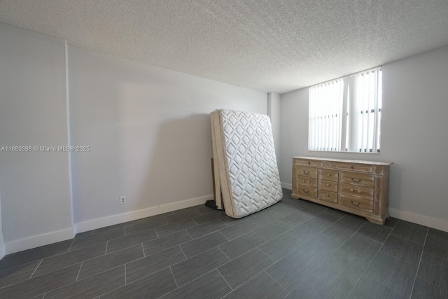 unfurnished bedroom with a textured ceiling and baseboards