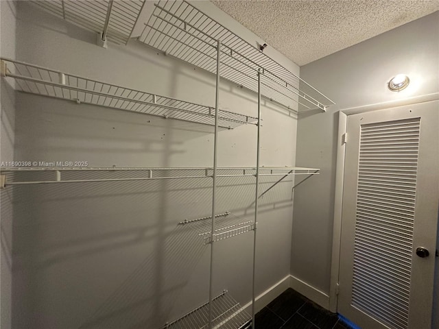 spacious closet featuring dark tile patterned flooring