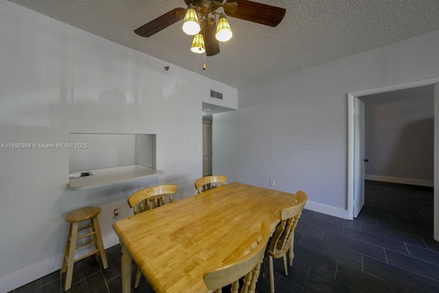 dining area featuring a textured ceiling, wood finish floors, a ceiling fan, visible vents, and baseboards