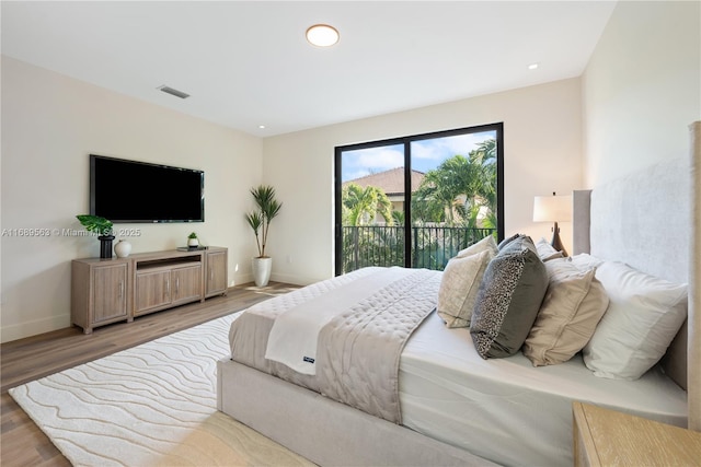 bedroom with access to exterior, visible vents, baseboards, and wood finished floors