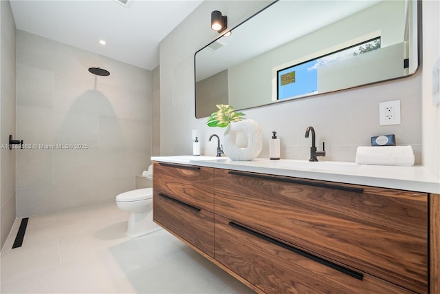 full bathroom with toilet, double vanity, a sink, and tile walls