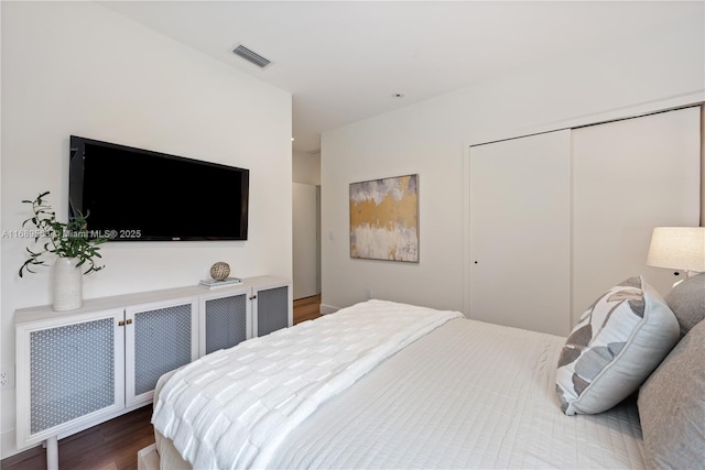 bedroom with a closet, wood finished floors, and visible vents