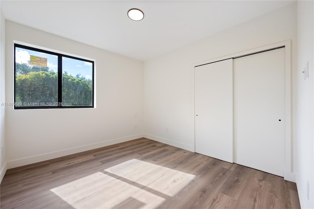 unfurnished bedroom with light wood-style flooring, baseboards, and a closet