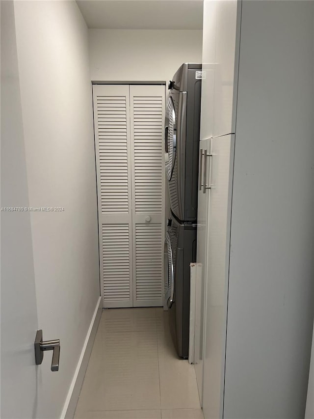 washroom featuring stacked washer and clothes dryer and light tile patterned flooring