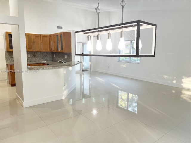 kitchen with high vaulted ceiling, light tile patterned floors, tasteful backsplash, and light stone countertops