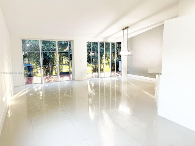 empty room with vaulted ceiling and light tile patterned flooring