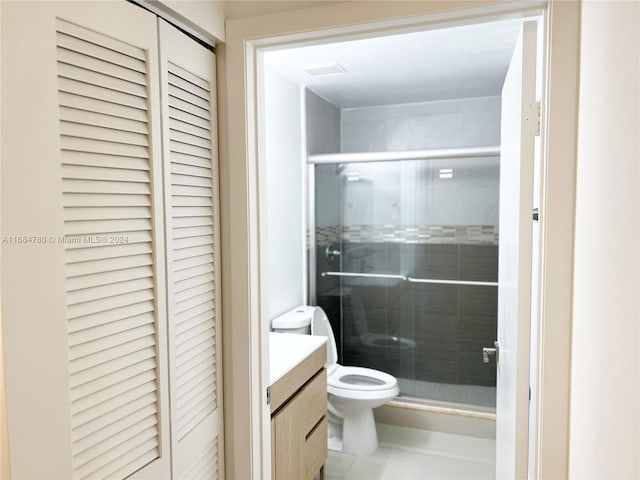 bathroom with toilet, vanity, tile patterned flooring, and a shower with shower door