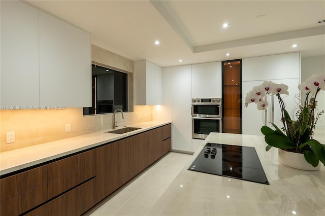 kitchen featuring white cabinets, sink, black electric cooktop, double oven, and dark brown cabinetry