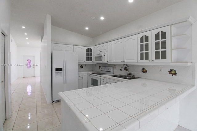 kitchen featuring tile countertops, white cabinetry, sink, white appliances, and lofted ceiling