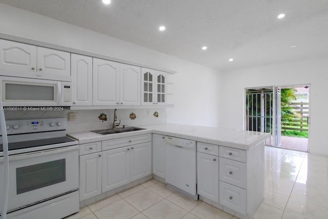 kitchen with kitchen peninsula, white appliances, tile counters, and white cabinets