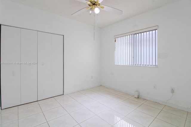 unfurnished bedroom with light tile patterned flooring, ceiling fan, and a closet