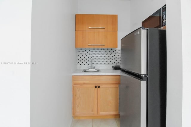 kitchen with backsplash, sink, and stainless steel fridge