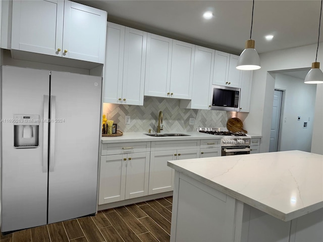 kitchen with white cabinets, hanging light fixtures, sink, appliances with stainless steel finishes, and dark hardwood / wood-style flooring