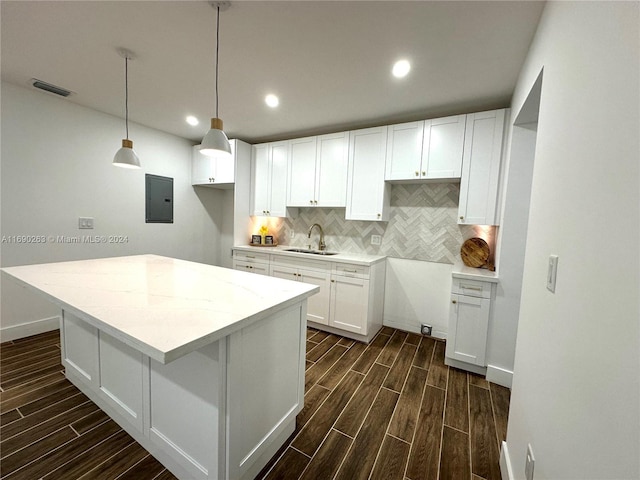 kitchen with dark hardwood / wood-style flooring, sink, decorative light fixtures, white cabinets, and electric panel