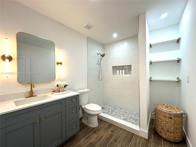 bathroom with vanity, toilet, and tiled shower