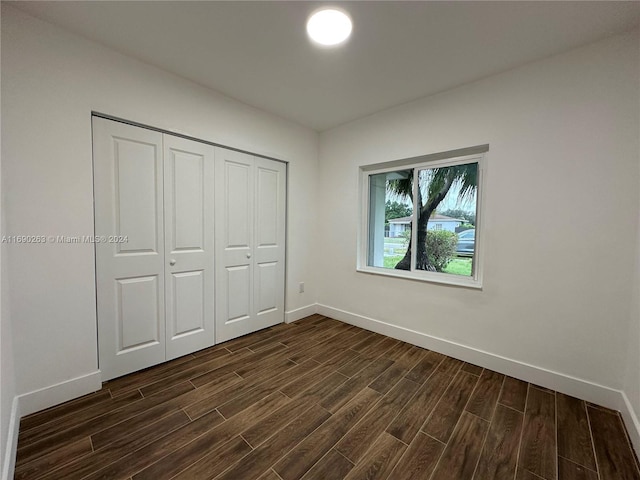 unfurnished bedroom with dark hardwood / wood-style flooring and a closet