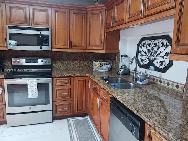 kitchen featuring appliances with stainless steel finishes, dark stone counters, sink, and tasteful backsplash