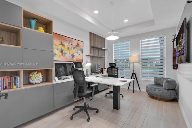 home office with light tile patterned floors and a tray ceiling