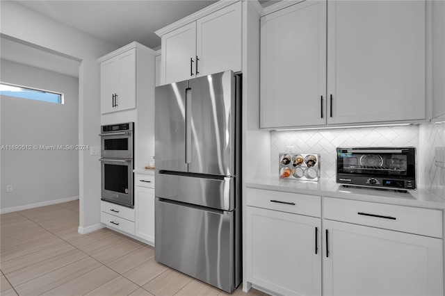 kitchen with white cabinets, decorative backsplash, light tile patterned floors, and stainless steel appliances