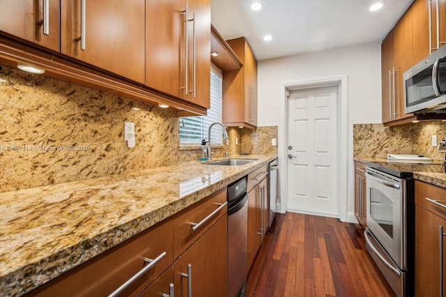 kitchen featuring stainless steel appliances, light stone counters, tasteful backsplash, and sink