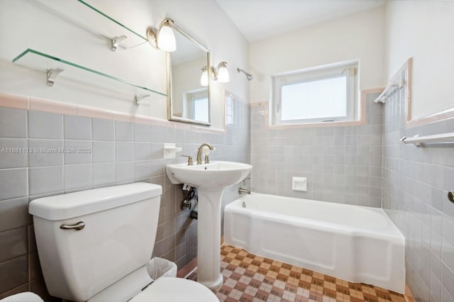 bathroom with tiled shower / bath combo, toilet, and tile walls