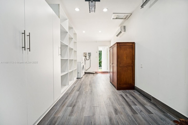 hall featuring wood-type flooring, washer / clothes dryer, and an AC wall unit