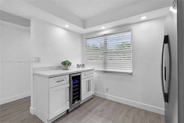 kitchen with white cabinets, stainless steel refrigerator with ice dispenser, beverage cooler, and light hardwood / wood-style floors