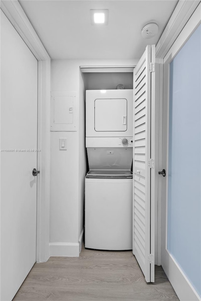 clothes washing area with stacked washer and dryer and light hardwood / wood-style flooring