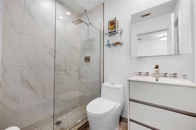 bathroom with hardwood / wood-style floors, vanity, toilet, and a tile shower