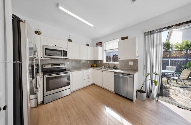 kitchen featuring stainless steel appliances, sink, tasteful backsplash, white cabinetry, and light hardwood / wood-style flooring