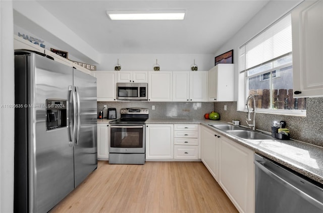 kitchen with stainless steel appliances, white cabinets, sink, and decorative backsplash