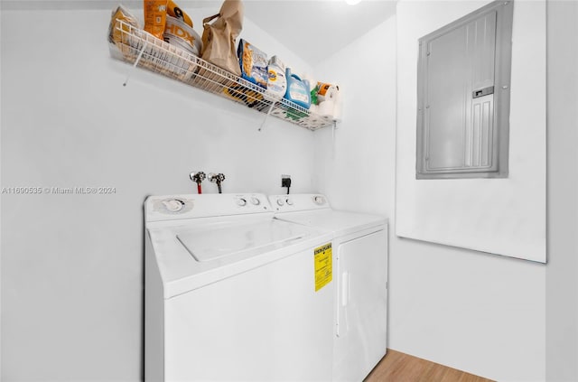 laundry area with electric panel, light hardwood / wood-style flooring, and washing machine and clothes dryer