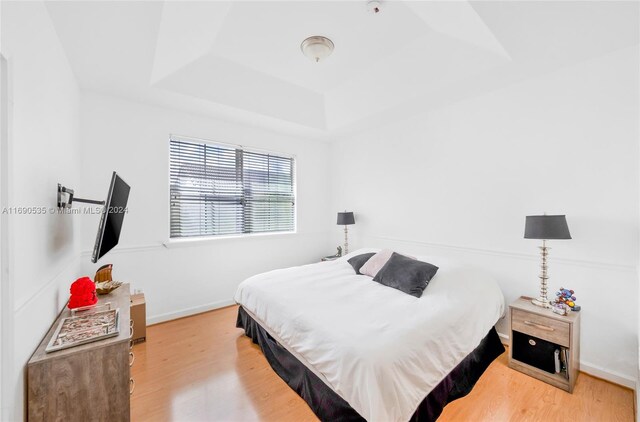 bedroom with hardwood / wood-style floors and a raised ceiling