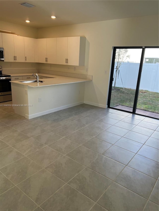 kitchen featuring kitchen peninsula, white cabinets, light tile patterned flooring, and stainless steel appliances