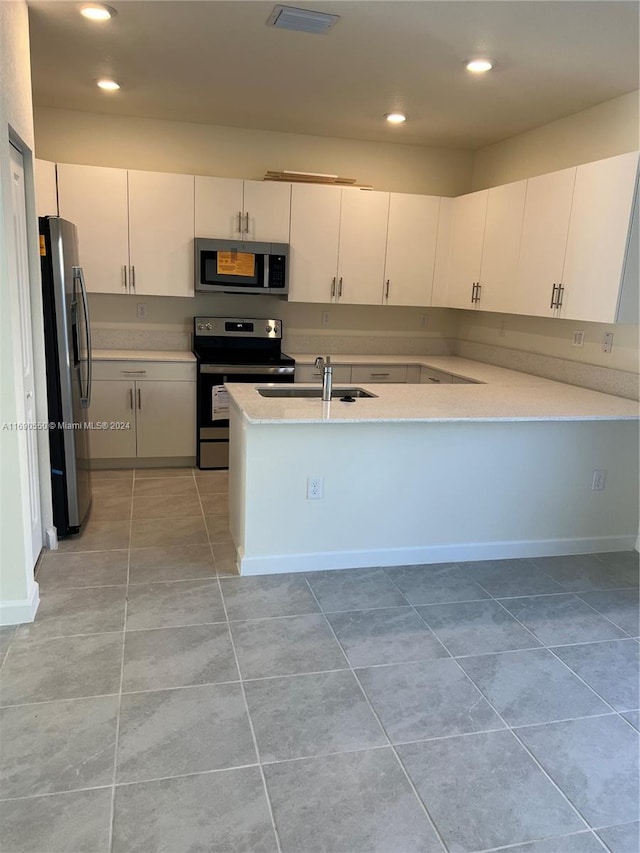 kitchen with light tile patterned flooring, sink, kitchen peninsula, appliances with stainless steel finishes, and white cabinets