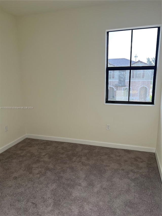 unfurnished room with dark carpet