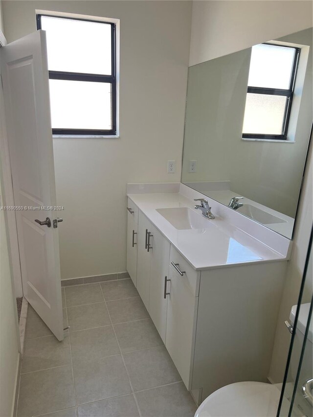 bathroom with vanity, a wealth of natural light, tile patterned floors, and toilet