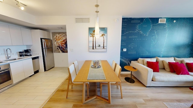 dining area with sink and light wood-type flooring